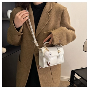 Sac bandoulière blanc en PU avec boucle en métal et pompon porté par un mannequin