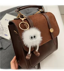 Close-up of vintage brown leather handbag with fuzzy monster charm and metal clasp