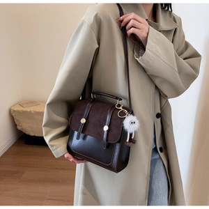 Sac à dos vintage en cuir marron avec pendentif en peluche porté sur un trench beige