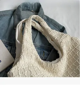 Detail of creamy white pleated tote bag showing bubble fabric texture and sturdy handle