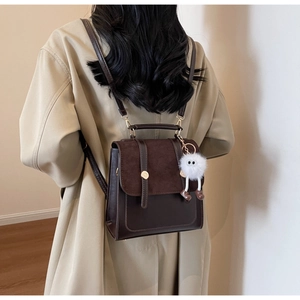 Sac à dos vintage marron foncé porté par un mannequin en manteau beige montrant sa taille