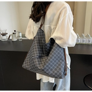 Detail of large tote bag with dark grey floral pattern and brown leather shoulder strap