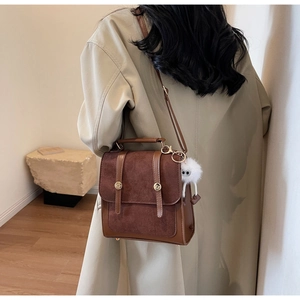 Détail d'un sac à dos vintage marron avec pendentif en peluche et boucle métallique