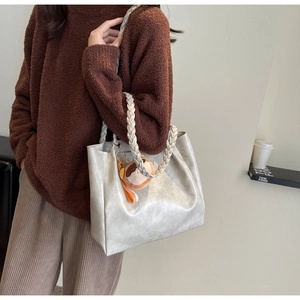 Close-up of beige tote bag with woven handles and cute plush charm detail