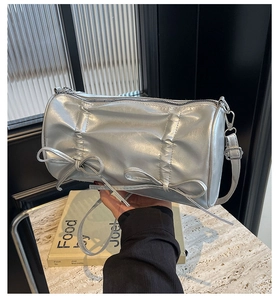 Detail of silver cylindrical handbag with gathered pleats and decorative ribbon bows