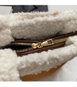 Detail des goldenen Reißverschlusses an der Tasche aus weißem Fleece und Leder
