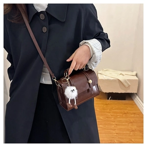 Vue détaillée d'un sac à bandoulière marron vintage avec un charmant pompon blanc
