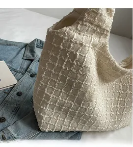 Detail of minimalist cream knit tote bag with 3D texture texture over denim jacket