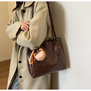 Brown large capacity tote bag with woven straps and plush charm on female model