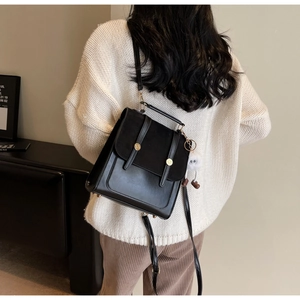 Détail d'un sac à dos vintage en cuir noir avec boucle dorée porté sur le dos