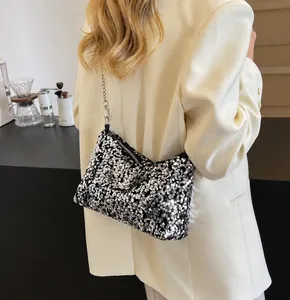 Silver sequin shoulder bag with chain strap shown on a model in a trendy outfit