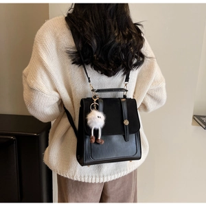 Vue arrière d'un sac à dos en cuir noir porté par un mannequin dans un intérieur minimaliste