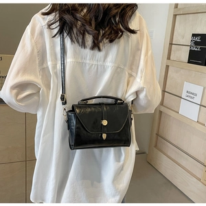 Détail d'un sac à bandoulière noir rétro avec boucle dorée et poignée supérieure