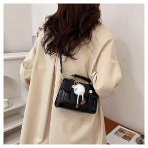 Détail du sac carré en cuir PU noir avec poignée supérieure et charmant pendentif en peluche
