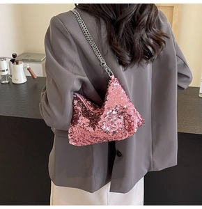 Detail of pink sequin shoulder bag with silver chain strap on a model shoulder