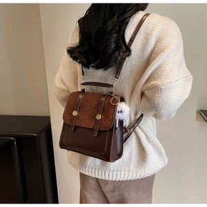 Détail d'un sac à dos vintage en similicuir marron avec pendentif peluche sur un mannequin