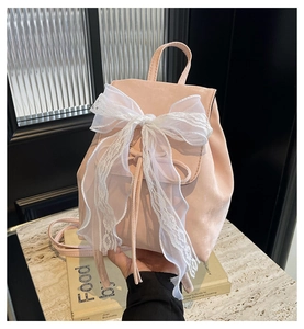 Close-up of pink ballet-style mini backpack featuring a large white lace bow detail
