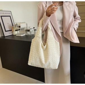 Close-up of white tweed tote bag showing textured weave fabric and spacious shoulder strap