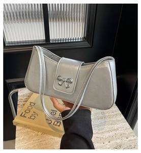 Detailsicht einer silbernen Baguette-Tasche mit stilvoller Schleife und Schultergurt