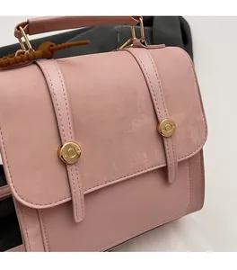Detail of pink crossbody bag showing matte texture and golden buckle hardware
