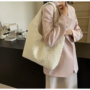 Detail view of a white pleated tote bag showing fabric texture in a lifestyle cafe setting