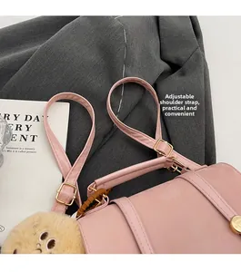 Detailed shot of pink leather handbag with adjustable strap and plush bear keychain decor