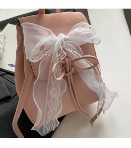 Close-up of pink faux leather backpack featuring a large white lace bow and soft texture
