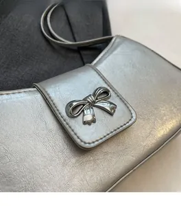Detail der silbernen Baguette-Tasche mit weicher Textur und Metall-Schleife