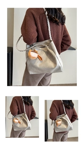 Detail of grey matte leather tote bag featuring unique braided shoulder strap and plush charm