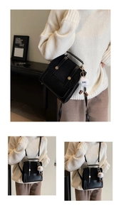 Detail of vintage black leather backpack with dual metal buckles and plush charm