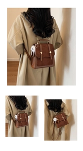 Detail of vintage brown suede backpack with gold buckles and plush charm on trench coat