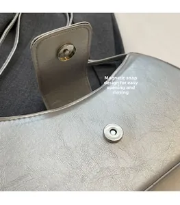 Nahaufnahme des magnetischen Metallverschlusses einer silbernen Retro-Unterarmtasche