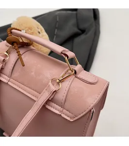 Detail of pink faux leather bag showing gold hardware and plush charm pendant