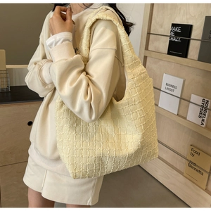 Close-up of light yellow pleated tote bag with textured fabric and matching shoulder strap