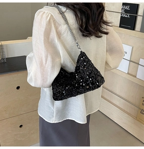 Detail of black sequined shoulder bag with silver chain strap worn by a model