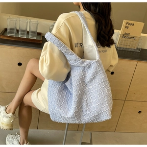 Detail of light blue pleated tote bag with waffle texture shown in casual lifestyle setting