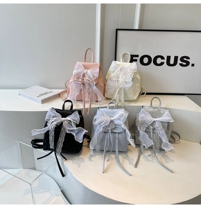 Mini backpacks with silk bows in pink, cream, black, blue, and grey displayed on steps