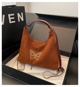 Close-up of brown suede hobo bag with gold butterfly embroidery in luxury gift box