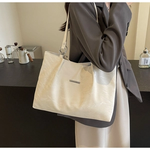 Chic cream tote bag with metallic bar detail shown in a stylish urban lifestyle setting