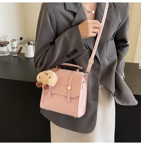 Detailansicht der rosa Umhängetasche mit Goldschnalle und Plüschanhänger am Model
