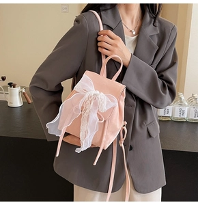 Chic pink ballet-style backpack with a large white lace bow shown on a model