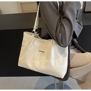 Detail of minimalist cream white tote bag with textured leather and silver metal bar