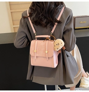 Detailansicht eines rosa Lederrucksacks mit goldenen Knöpfen und Plüsch-Koala-Anhänger
