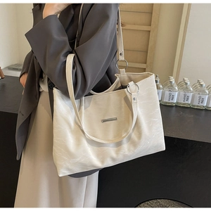 Detail of cream white PU leather tote bag featuring silver metal accents and spacious design