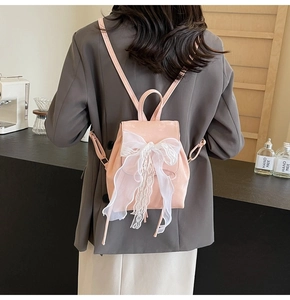 Detailed back view of a pink backpack with a large white lace bow and silk ribbons