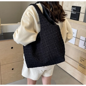 Close-up of black pleated tote bag with bubble texture and waffle pattern details