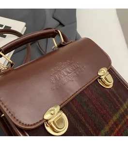Detailed close-up of brown textured flap with gold snap buttons and checked fabric