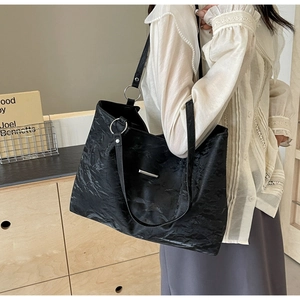 Detail of black tote bag with wrinkled texture and silver metal hardware accents