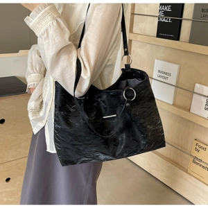 Close-up of black tote bag featuring unique crinkled texture and silver metal hardware