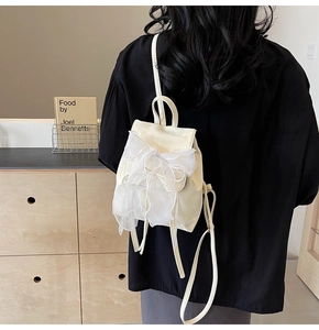 Detail of a creamy white mini backpack with a large sheer organza bow on the back